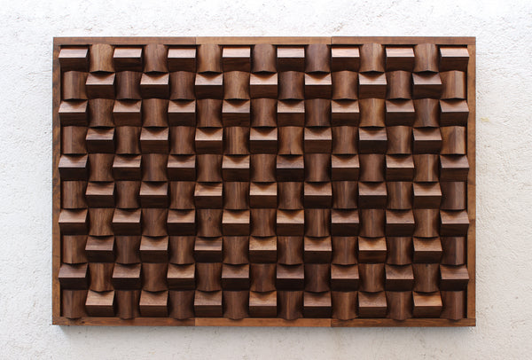 Panel acústico decorativo de madera montado sobre muro blanco. Diseño artístico tridimensional que combina funcionalidad acústica y estética moderna. Hecho a mano por Artelier en México.